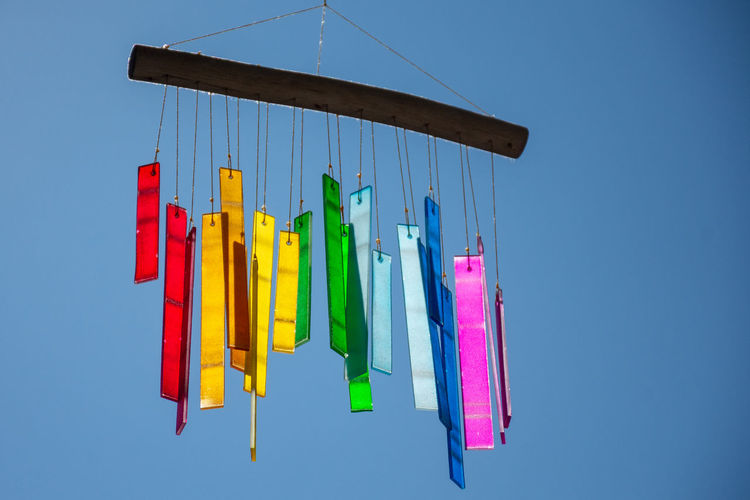 Close-up of multi colored clothespins on clothesline against blue sky