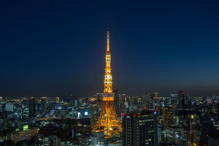 Illuminated tokyo tower in city against sky at night