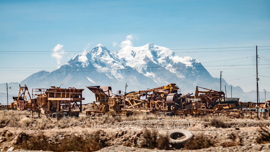 Abandoned construction machinery against on field against snowcapped mountain