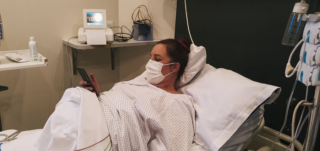Pregnant young woman dilating in delivery room, using smartphone person