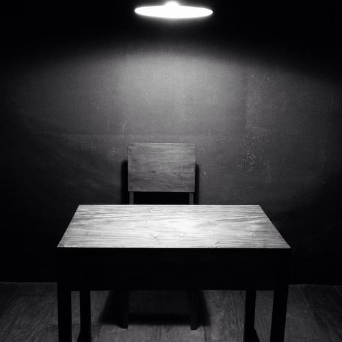 Empty chairs and table against wall