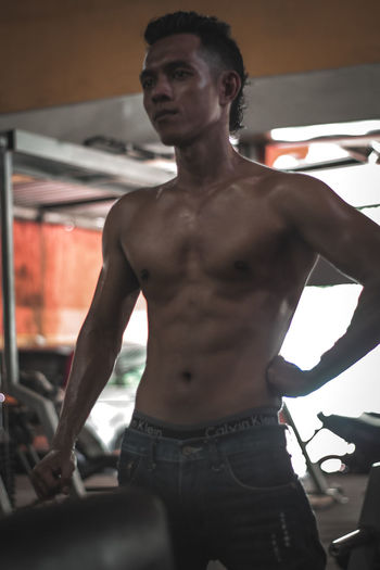 Portrait of shirtless young man standing at home