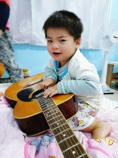 Cute boy playing guitar at home
