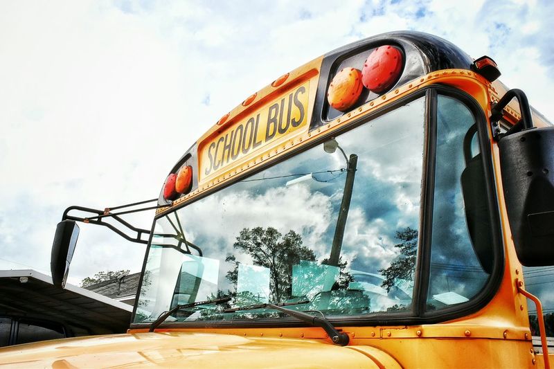Close-up high section of school bus against clouds