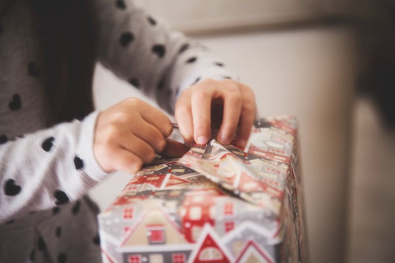 Midsection of woman opening wrapping paper on gift