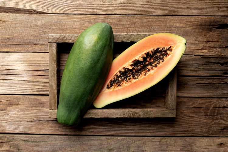 Fresh tropical papaya fruit in wooden delivery box on wooden background flat lay top view with space