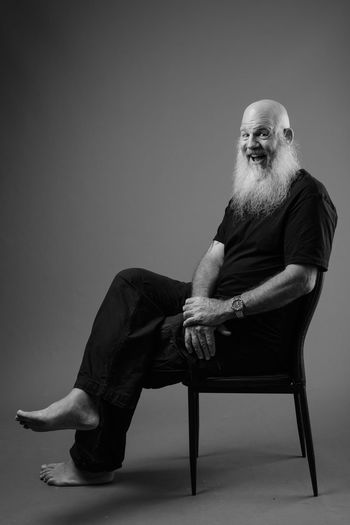 Portrait of man sitting on chair against wall