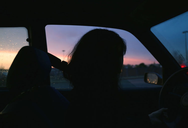 Rear view of woman looking through car window