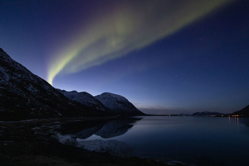 Scenic view of lake and mountains against sky at night