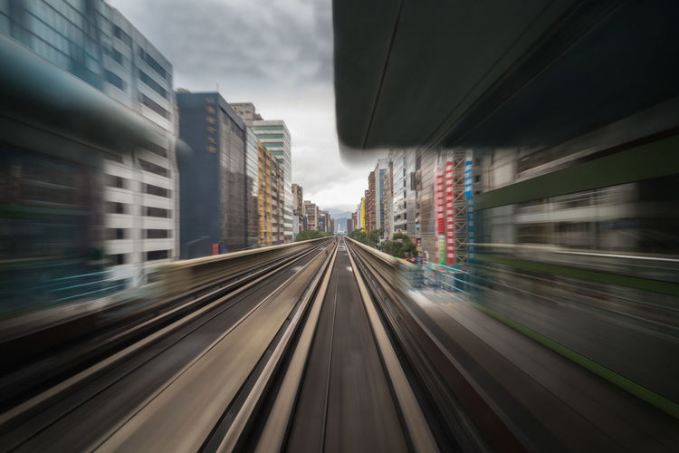 Blurred motion of railroad station against buildings in city