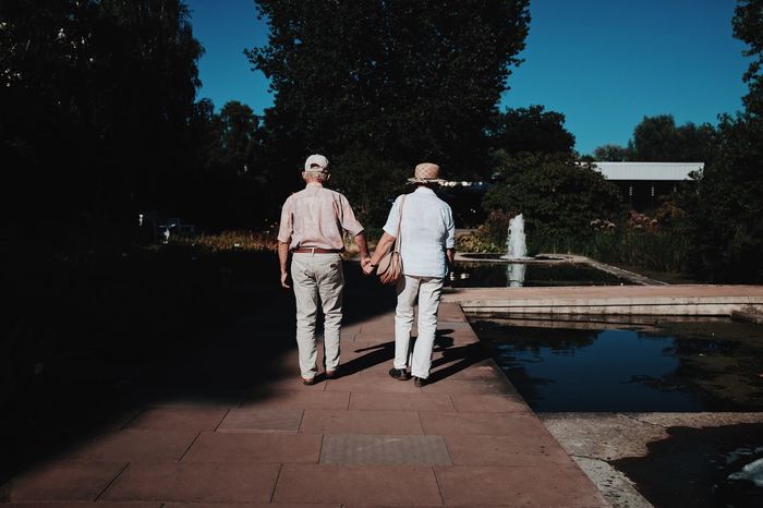Rear view of senior couple walking on footpath in park