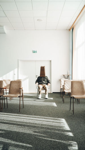 View of man sitting in the room with empty chairs