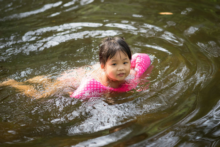 Cute girl with water wings swimming in lake