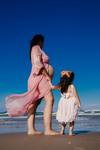 Rear view of women on beach against clear blue sky