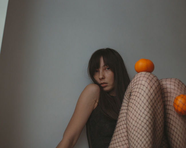 Sad woman in black lingerie ant fishnettights with mandarins