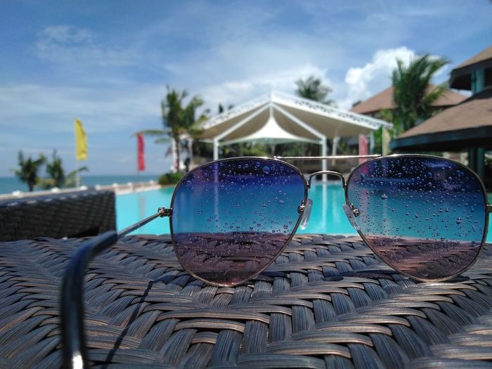Close-up of sunglasses on chair against swimming pool
