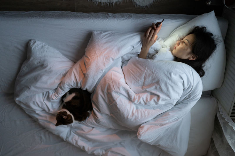 Life apathy. unmotivated young woman in bed staring at smartphone screen, suffer from sleep desorder