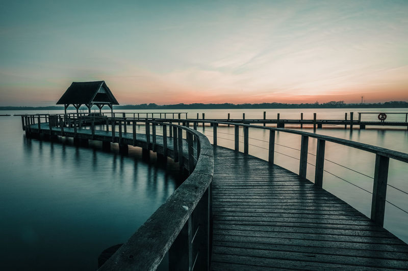 Pier over sea against sky during sunset