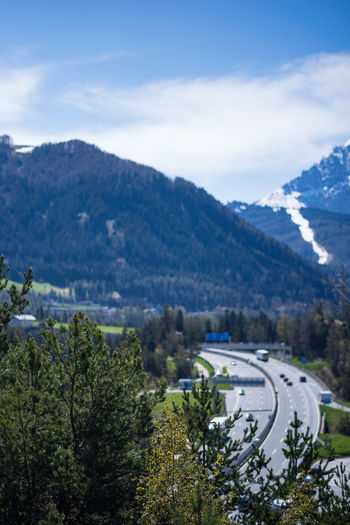 Road by trees and mountains against sky