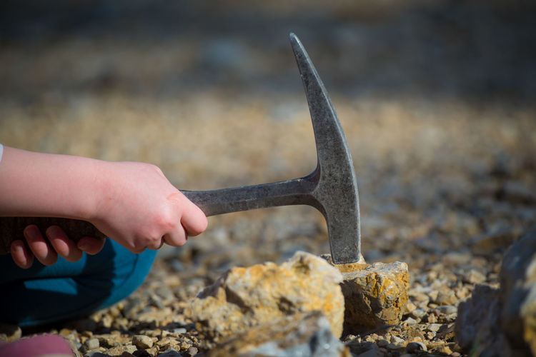 Close-up of hand hammering rock with equipment