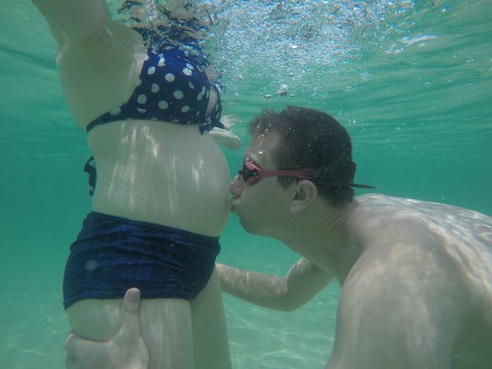 Man kissing stomach of pregnant woman in swimming pool