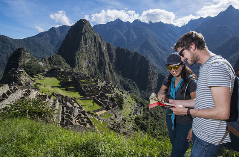 Couple at inca ruins looking at folding map, machu picchu, peru