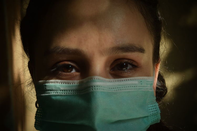 Close-up portrait of mid adult woman covering face