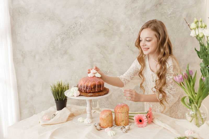 Smiling girl garnishing cake at home