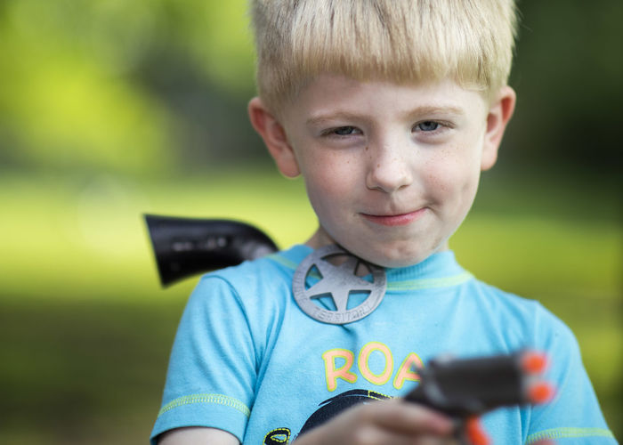 Portrait of boy holding smart phone outdoors