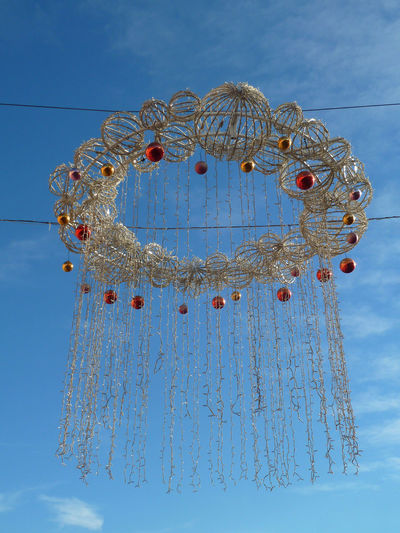 Low angle view of christmas decoration hanging against blue sky