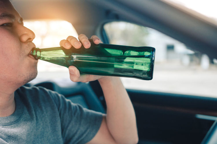 Man drinking beer while sitting in car 