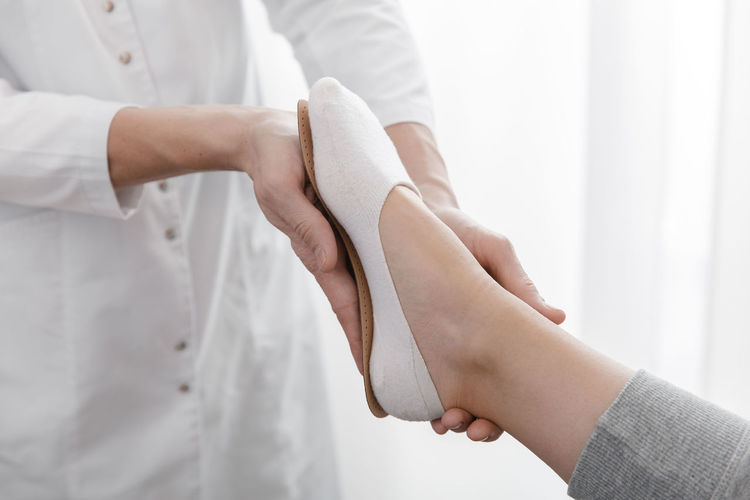 Cropped hand of doctor holding insoles by patient feet