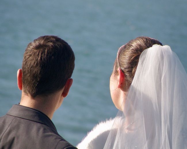 Rear view of newlywed couple looking at sea