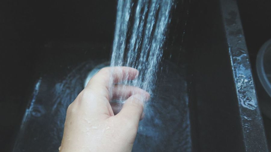 Cropped image of person washing hand in sink
