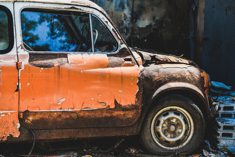 Old rusty car parked at junkyard