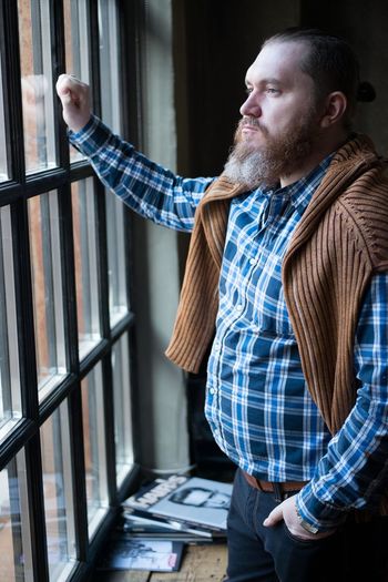 Thoughtful man wearing suspender looking through window at home