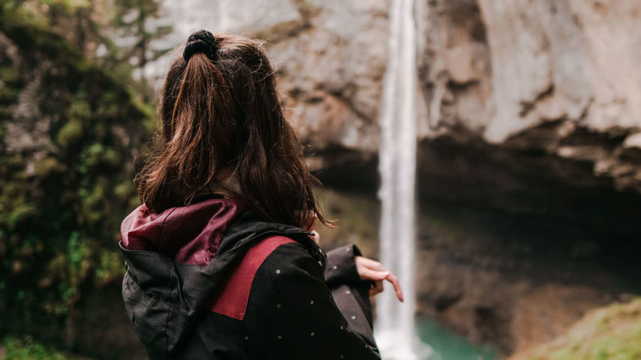 Side view of woman looking at waterfall in forest