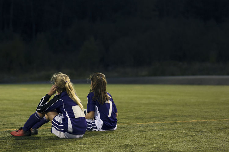 Rear view of women sitting on field