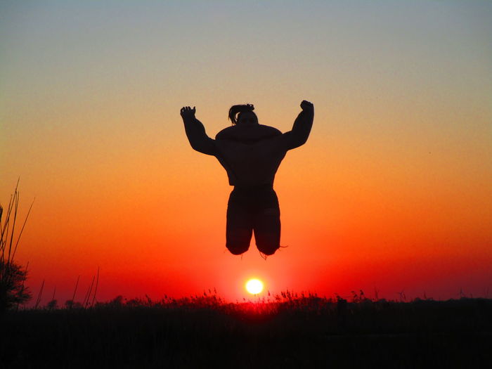 Silhouette girl jumping against sky during sunset