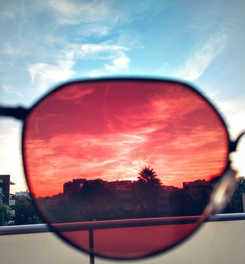 Close-up of sunglasses on side-view mirror against sky