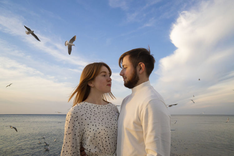 Young couple on beach against sky