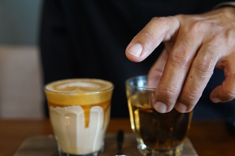 Close-up of hand holding drink on table