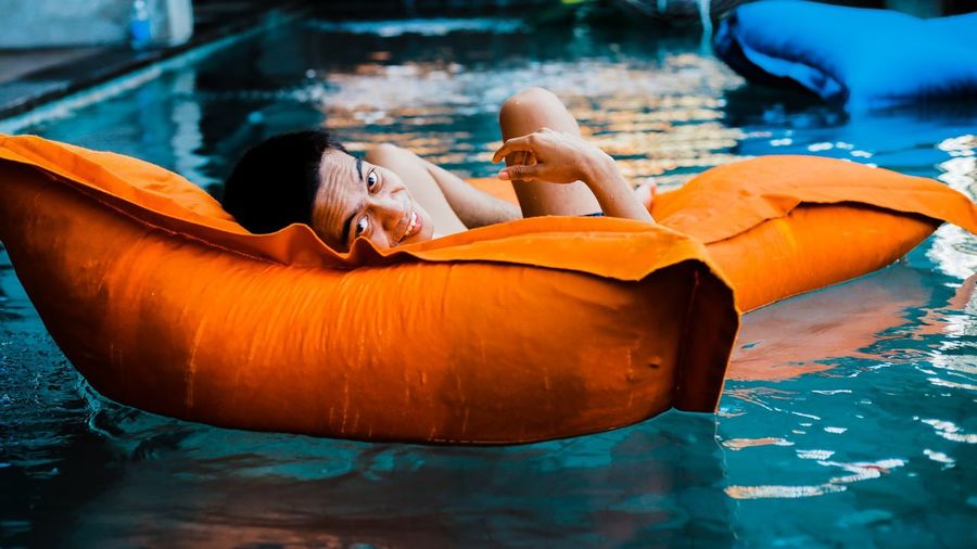 Portrait of man relaxing on pool raft in swimming pool