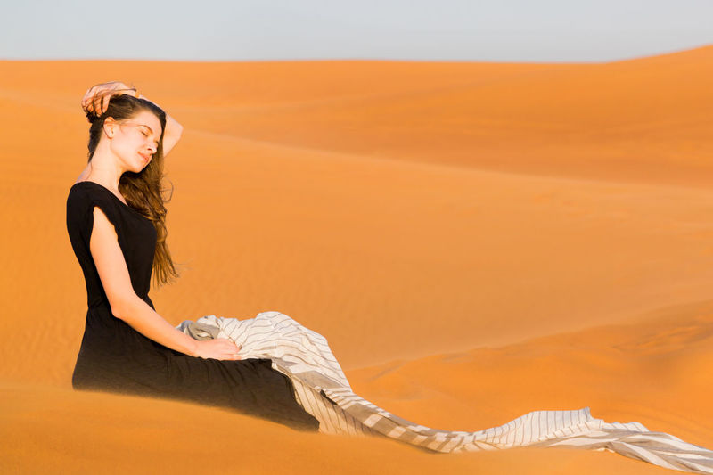 Side view of young woman in desert during sunset
