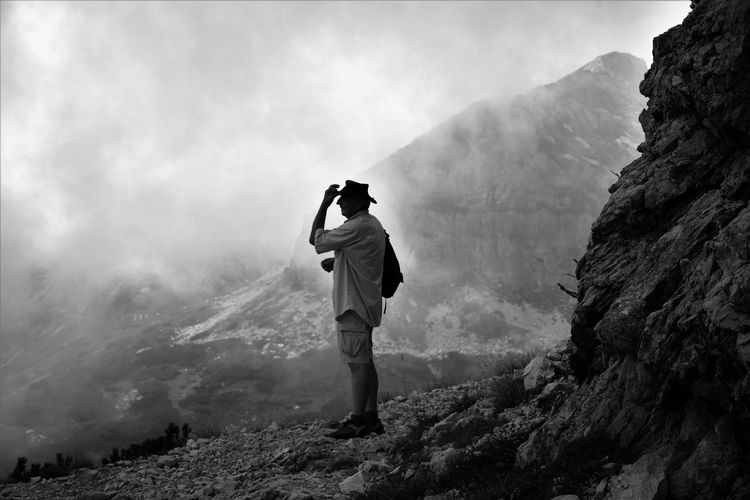 Full length of man standing on mountain against cloudy sky