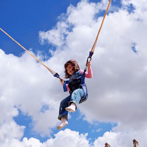 Low angle view of girl bungee jumping against sky