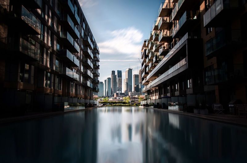 Canal amidst buildings against sky in city