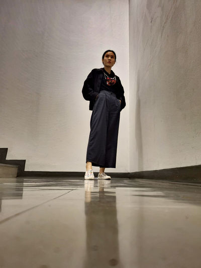 Full length of asian woman standing against wall at the fire exit entrance