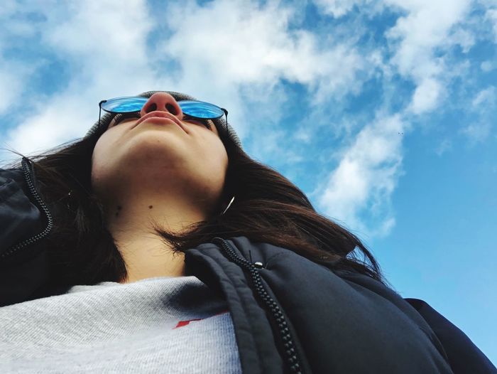 Low angle view of woman wearing sunglasses against sky