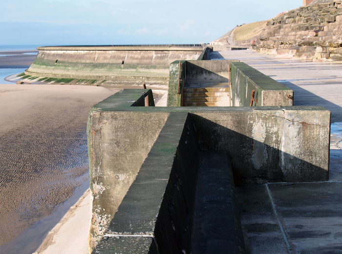 Concrete stairs on seawall in blackpool with the beach at low tide in sunlight